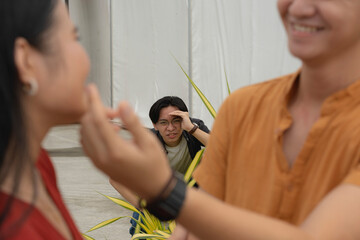 A young man spies on his ex-girlfriend with a new man while hiding behind some bushes. A...