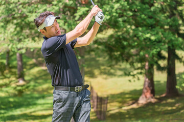 ゴルフ場でゴルフをするゴルファーの男性
