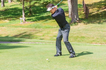 ゴルフ場でゴルフをするゴルファーの男性
