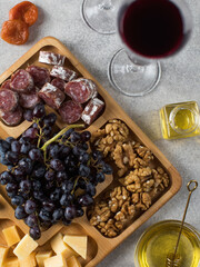  Snacks for wine in a wooden menagerie. Cheese, sausages, berries in a plate, festive serving of snacks.