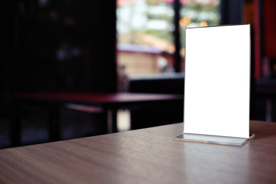 Mock up Menu frame standing on wood table in Bar restaurant cafe. space for text