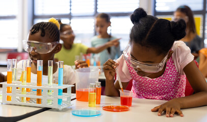 Diverse schoolgirls with chemistry items and liquids in elementary school class