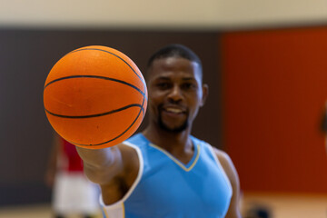 Portrait of happy african american male basketball player holding basketball at gym