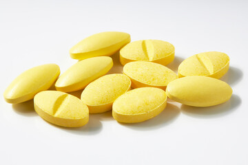 Many oval-shaped yellow pills isolated on a white background.