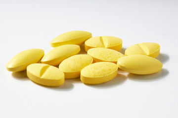 Many oval-shaped yellow pills isolated on a white background.