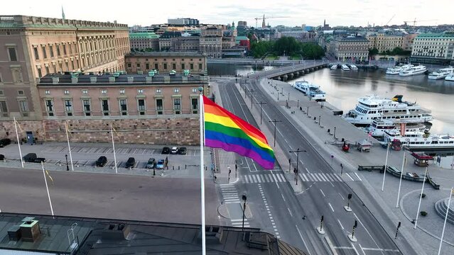 Aerial view at huge LGBTQ flag over Stockholm. Sex minority banner waving in wind sky above town. Rainbow flag towards midtown. Gay pride diversity tolerance freedom symbol, transgender rights