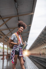 Young woman female smiling traveler with back pack looking to map while waiting for the train at train station. High quality photo