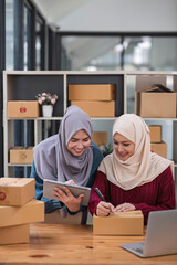 Friend muslim female work independent business sme online shopping working on laptop computer with parcel box on desk at home, SME online business and delivery concept