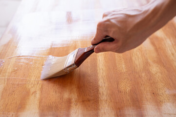Apply clear wood stain on table with brush
