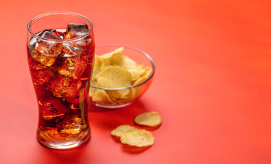 Refreshing glass of cola with ice, accompanied by a serving of crispy chips