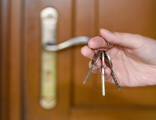 Trzymać pęk kluczy do domu w dłoniach na tle drzwi - obrazy, fototapety, plakaty
