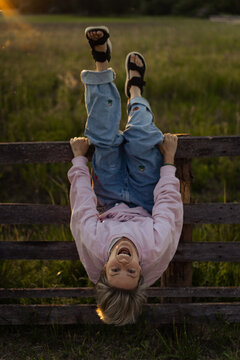 Woman in the countryside sits on a fence and fool around, having funю