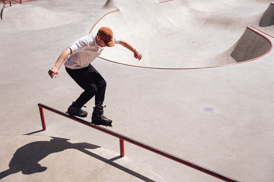 aggressive roller skater performing a trick on a railing in skatepark