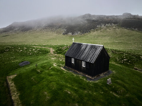Old abandoned black wooden chapel on foggy day
