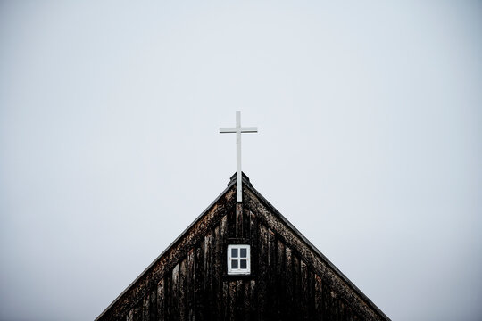 Weathered wooden church with cross on roof against overcast sky