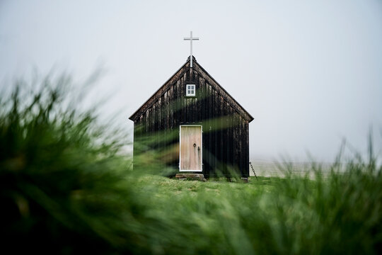 Small black church with cross on top of it
