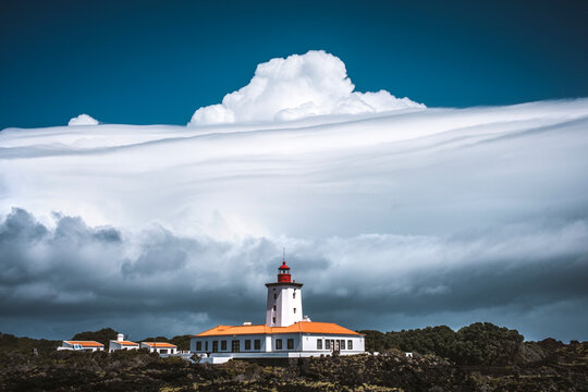 Dramatic thunder clouds build above a lighthouse, Pico, Azores