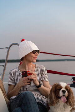 Young woman on a yacht with a dog, Cavalier King Charles Spaniel