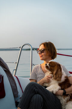 Young woman on a yacht with a dog, Cavalier King Charles Spaniel