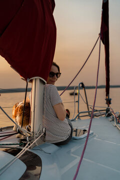 Young woman on a yacht with a dog, Cavalier King Charles Spaniel