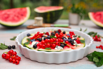 Fruity watermelon pizza with seasonal fruits on the garden table.
