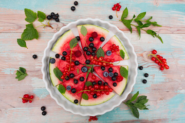 Fruity watermelon pizza with seasonal fruits on the garden table.