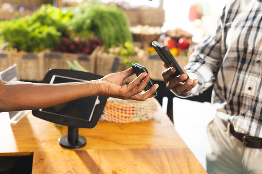 Midsection of senior african american man paying with smartphone at health food organic grocer