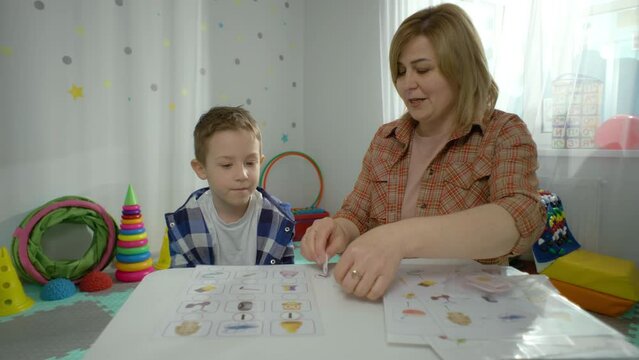 A preschool boy works individually with a teacher in kindergarten. The child learns letters and plays educational games in preparation for school. High quality 4k footage