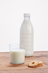 glass cup with milk and plastic bottle on wooden rustic table