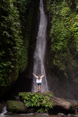 A woman standing in front of waterfall in the jungle. Travel Indonesia. Hidden beauty of the island