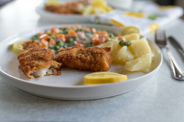 Breaded fish with peas and carrots in a bechamel sauce. Served with boiled potatoes on a plate