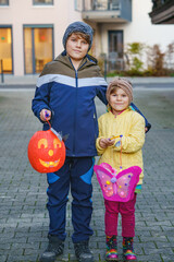 Little toddler girl and school kid boy holding selfmade lanterns with candle for St. Martin...