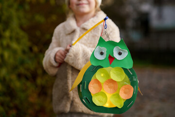 Little preschool kid girl holding selfmade traditional owl lanterns with candle for St. Martin...