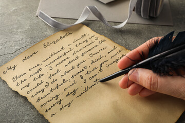 Letter with text and pen in hand on gray background, close up