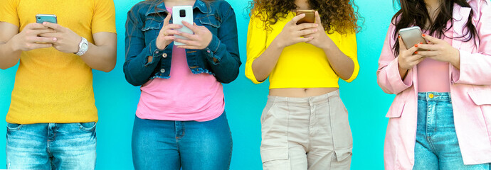 Group of young millennial friends in colorful clothes using smart mobile phone - Teenagers...