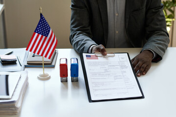 Close-up of African American manager sitting at table with blank in visa centre