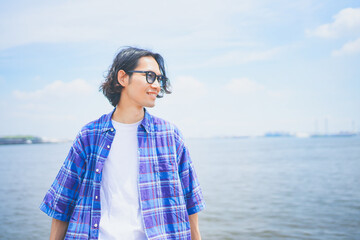 夏空の下で海風を感じる男性のポートレート