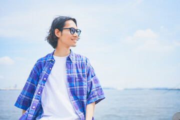 夏空の下で海風を感じる男性のポートレート