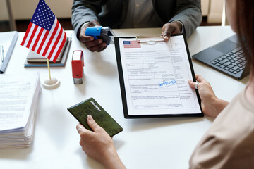 Close-up of young woman sitting at table with manager and getting her international documents - obrazy, fototapety, plakaty
