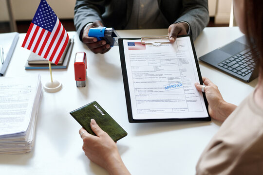 Close-up of young woman sitting at table with manager and getting her international documents