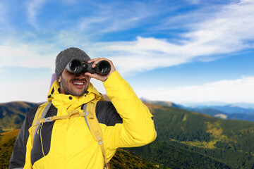Tourist with backpack and binoculars in mountains