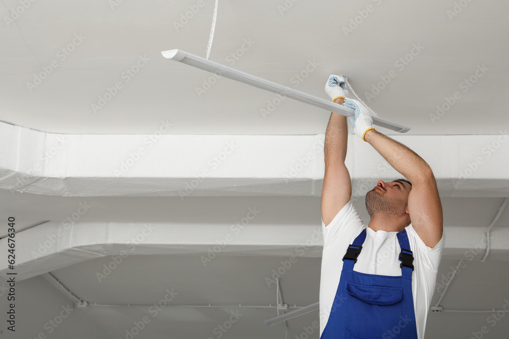 Poster Electrician installing led linear lamp indoors, space for text. Ceiling light