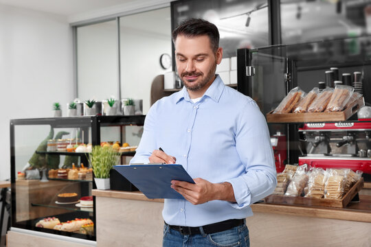 Business owner with clipboard in his cafe