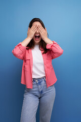 smiling brunette woman with hair below her shoulders in a shirt closed her hands in anticipation of a surprise