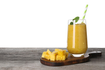 Glass of tasty pineapple smoothie and cut fruit on wooden table against white background, space for text