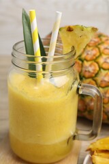 Tasty pineapple smoothie and fruit on table, closeup