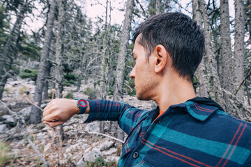 Hiker man with wristwatch in the woods on a trail