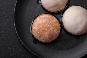 Delicious sweet mochi dessert with toppings on a dark concrete background