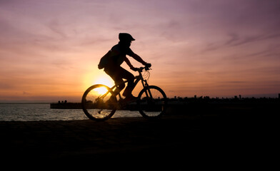 Obraz na płótnie Canvas Silhouette of cyclist biking at the sunset