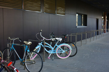 Parked multicolored bicycles near the dark grey wall of a modern building. Parking, street transport. Poland, Wroclaw, January 2023.